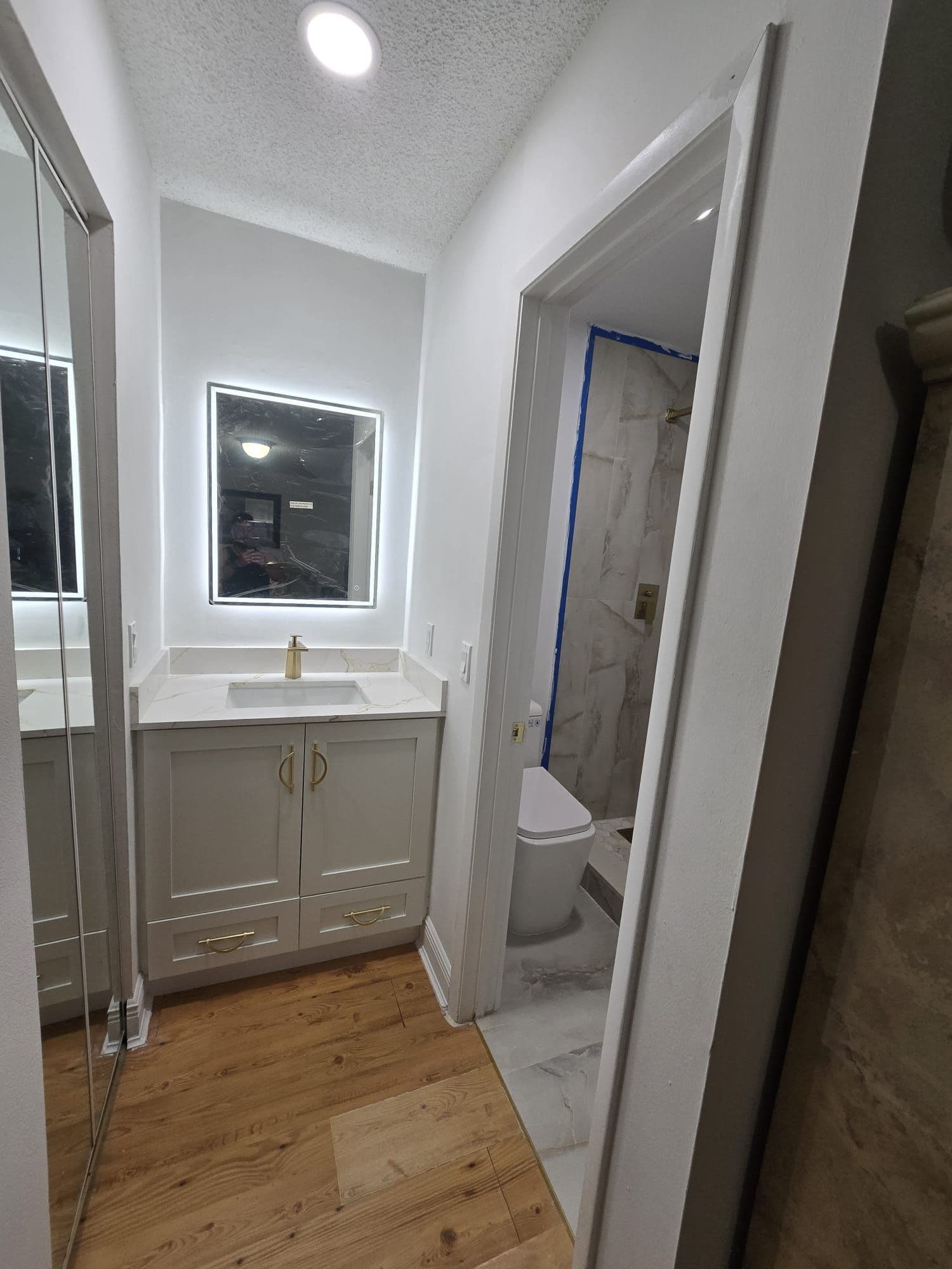 Vanity with an LED mirror and gold fixtures from a D&H Kraft bathroom remodel