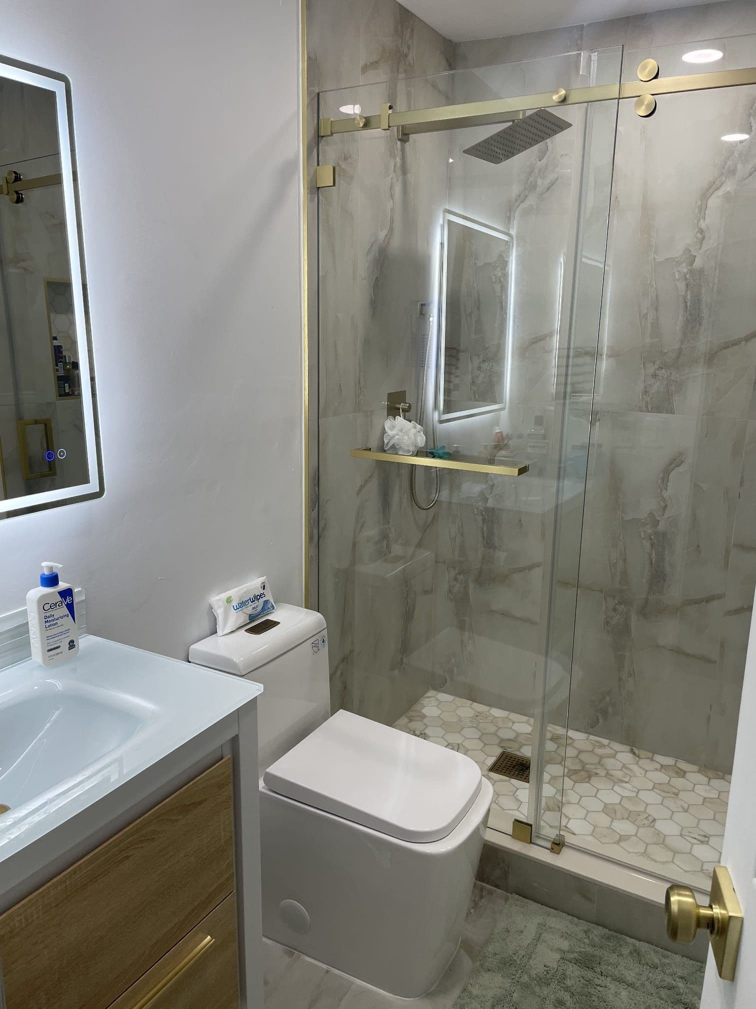 Marble walk-in shower with gold hardware completed by D&H Kraft Construction